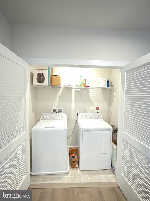 washroom featuring laundry area, wood finish floors, and washing machine and dryer