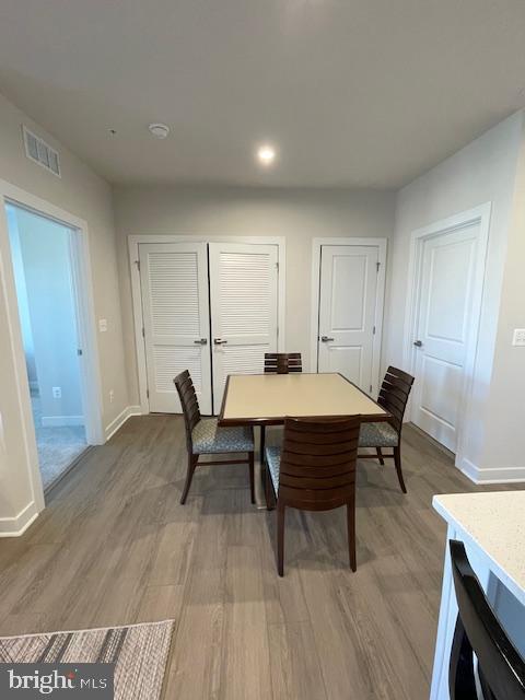 dining area with light wood finished floors, baseboards, and visible vents