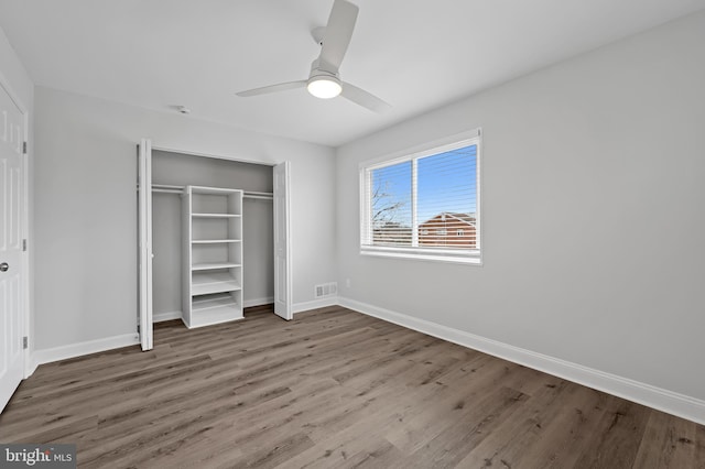 unfurnished bedroom featuring baseboards, a closet, visible vents, and wood finished floors