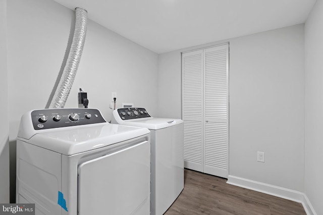 clothes washing area featuring laundry area, baseboards, washing machine and clothes dryer, and wood finished floors