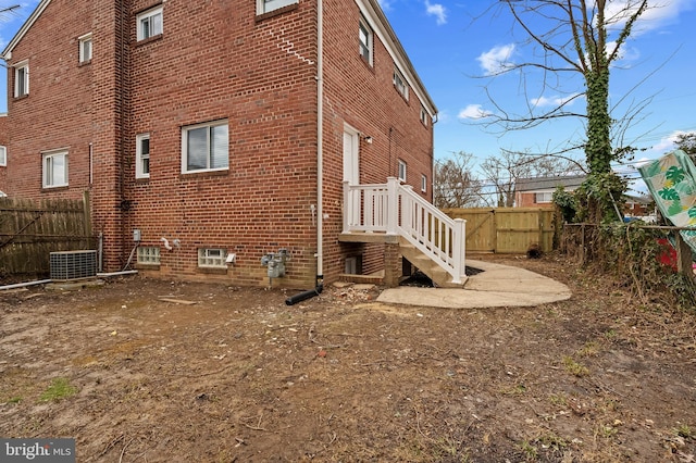 view of property exterior with fence, cooling unit, and brick siding