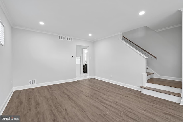 unfurnished living room with stairway, crown molding, visible vents, and wood finished floors