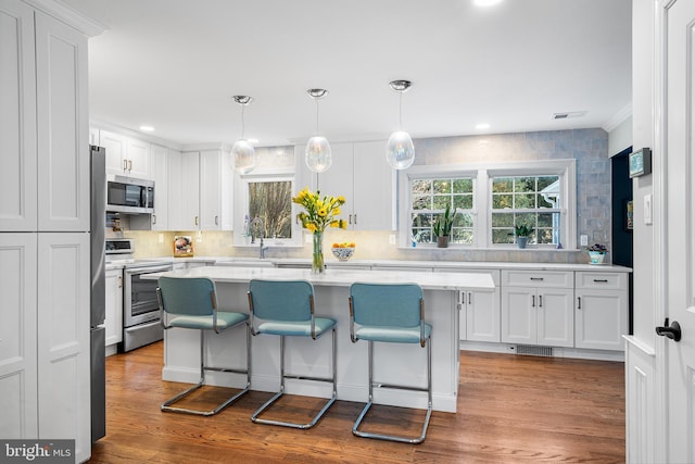 kitchen with dark wood-style flooring, white cabinetry, stainless steel appliances, and light countertops