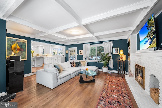 living area featuring a fireplace, beam ceiling, and wood finished floors