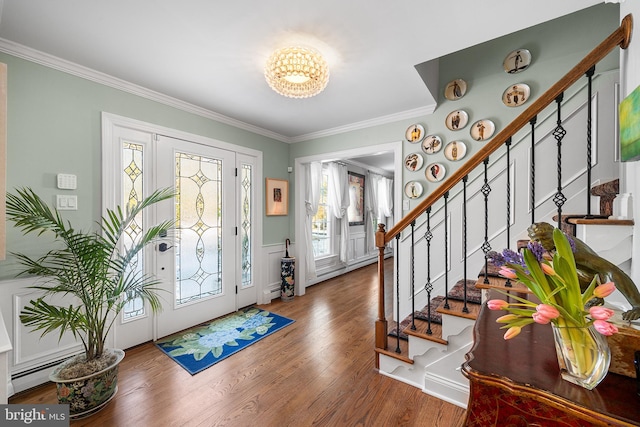 foyer featuring stairway, an inviting chandelier, ornamental molding, a baseboard heating unit, and wood finished floors