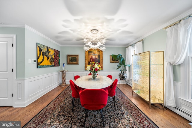 dining room with wainscoting, wood finished floors, and crown molding