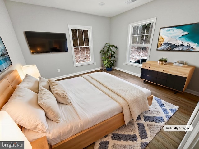 bedroom with visible vents, baseboards, and wood finished floors