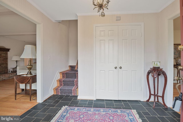 entryway featuring wood finished floors, crown molding, and stairs