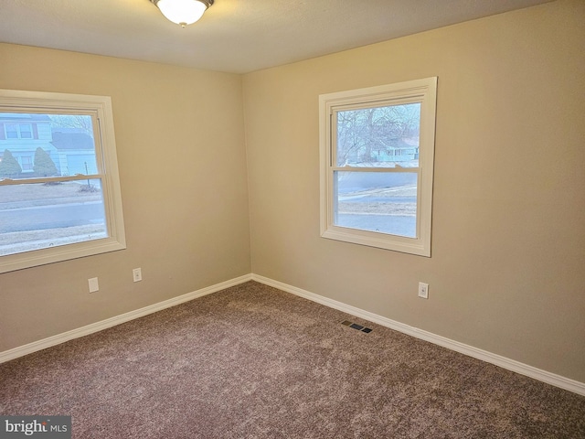 empty room featuring baseboards, visible vents, and carpet flooring