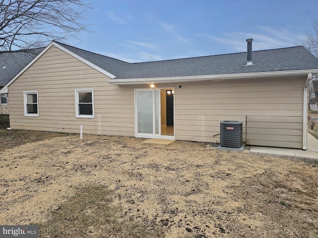 back of property with a shingled roof and central AC unit