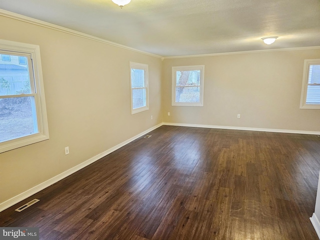 empty room featuring dark wood-style flooring, visible vents, crown molding, and baseboards