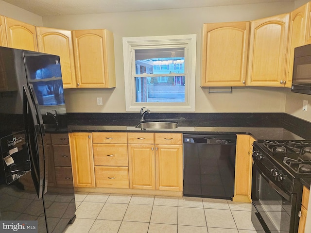 kitchen featuring black appliances, light brown cabinetry, dark countertops, and a sink