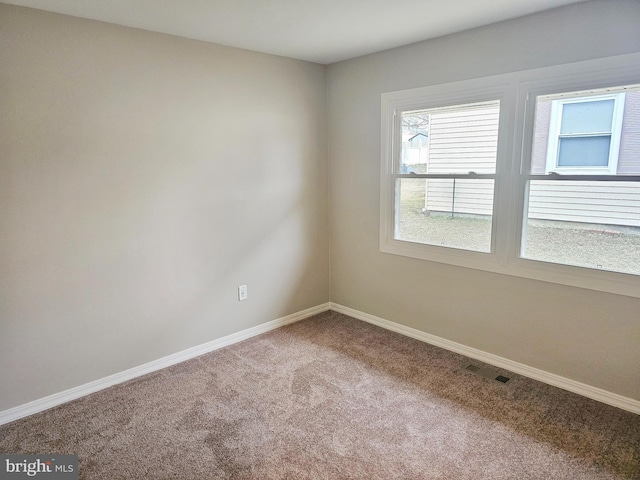 carpeted spare room featuring visible vents and baseboards