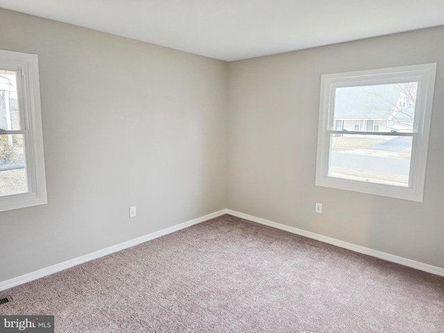 carpeted empty room with visible vents and baseboards