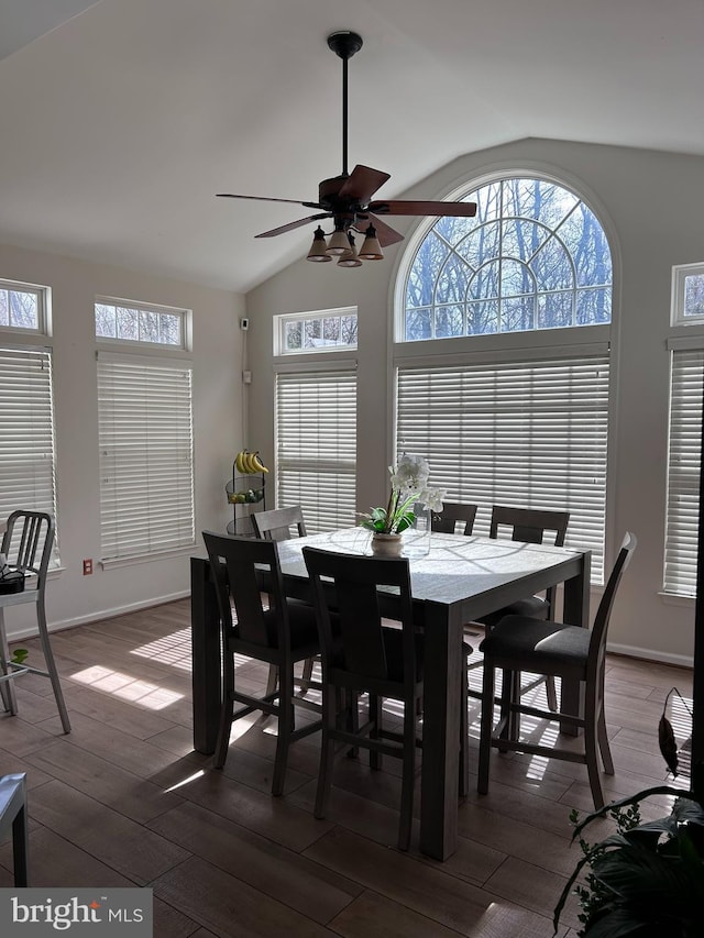 dining room with baseboards, dark wood-type flooring, ceiling fan, and vaulted ceiling