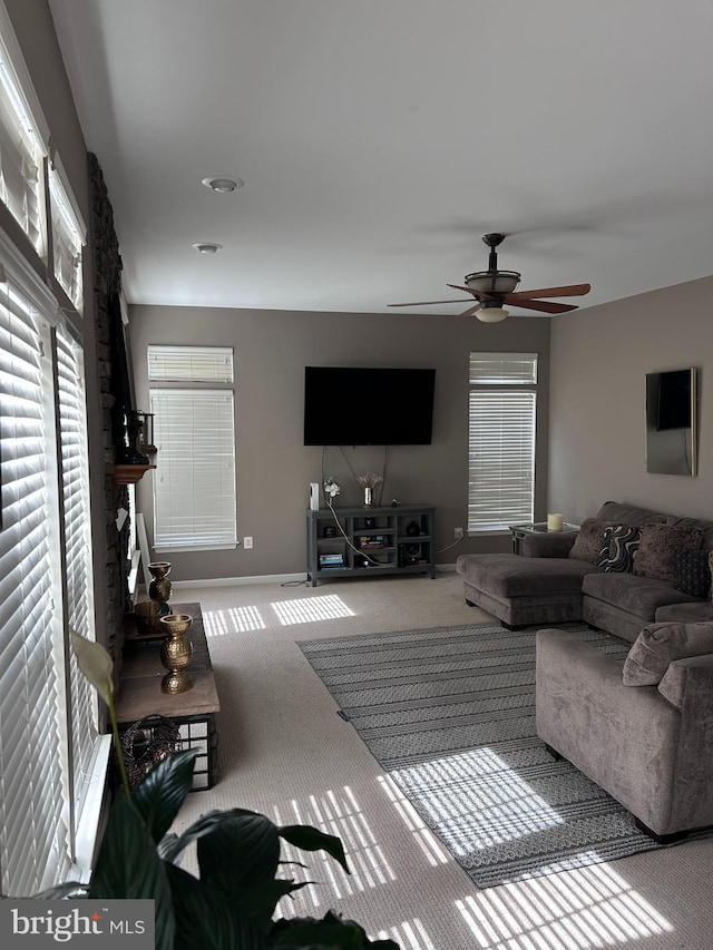 carpeted living room with a ceiling fan and baseboards