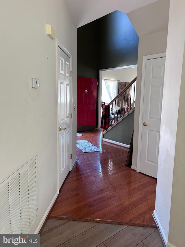 hall featuring visible vents, stairs, baseboards, and hardwood / wood-style flooring