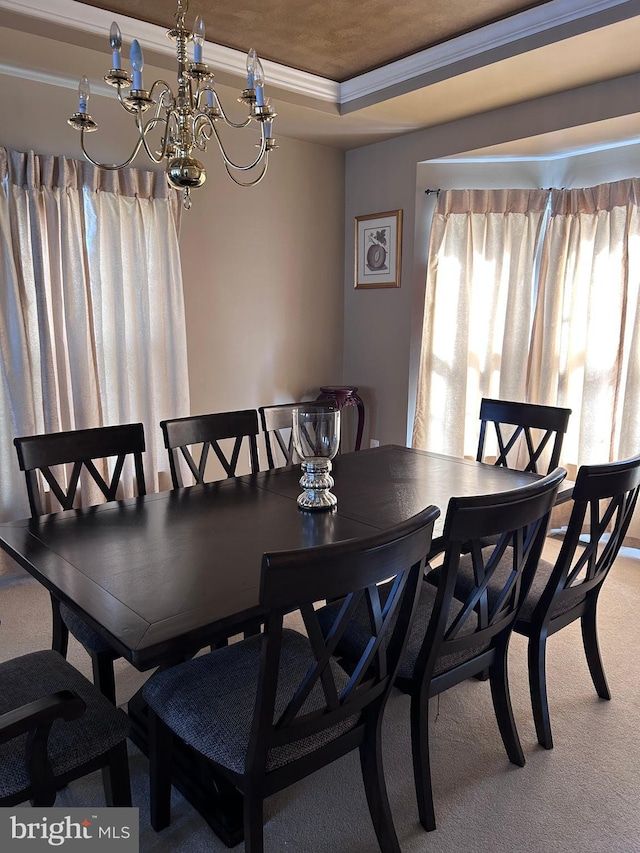 dining space with a chandelier, crown molding, a raised ceiling, and carpet floors