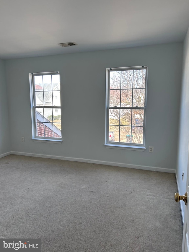 carpeted spare room featuring visible vents and baseboards