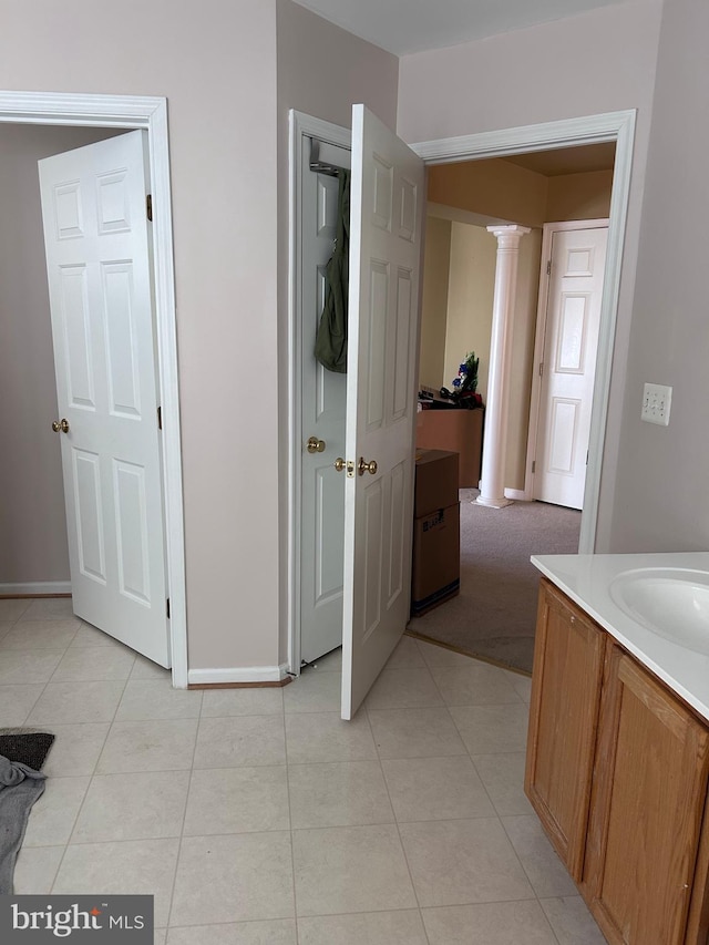 bathroom with tile patterned floors, baseboards, ornate columns, and a sink