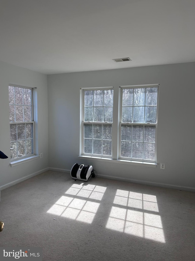 unfurnished room with visible vents, carpet floors, and baseboards