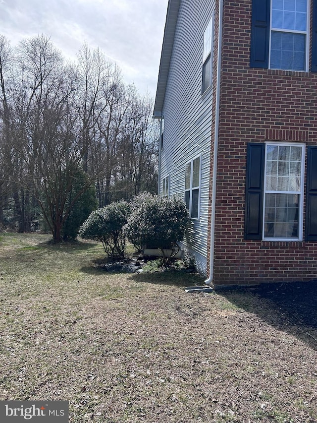 view of side of property with brick siding and a lawn