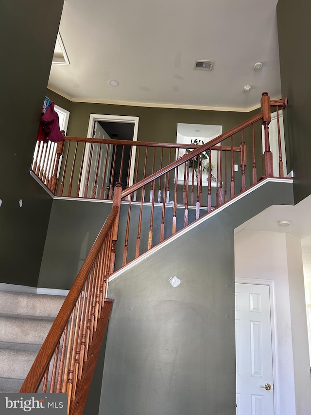 stairs featuring visible vents and ornamental molding