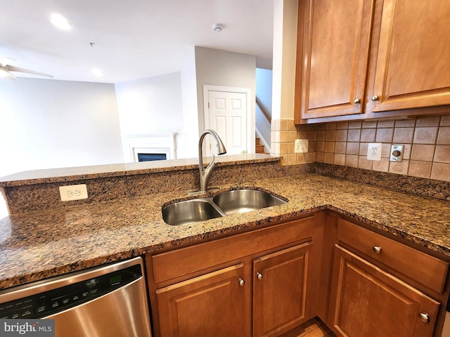 kitchen featuring a sink, dark stone countertops, backsplash, and stainless steel dishwasher