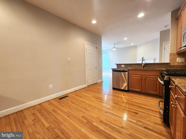 kitchen with stainless steel dishwasher, gas stove, a sink, and light wood-style floors