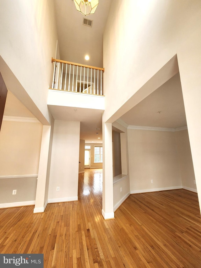 entrance foyer with ornamental molding, visible vents, baseboards, and hardwood / wood-style flooring