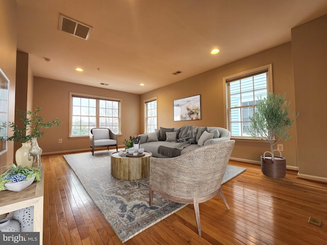 living area with hardwood / wood-style floors, visible vents, and baseboards