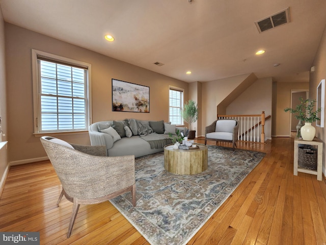 living area with wood-type flooring, visible vents, baseboards, and recessed lighting