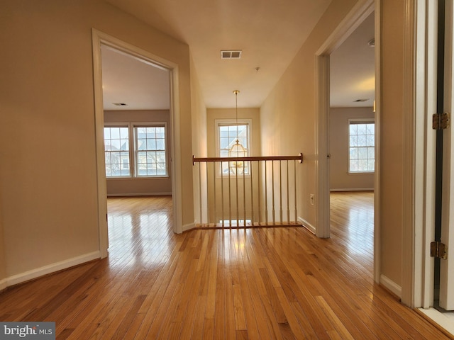 hall with baseboards, visible vents, plenty of natural light, and hardwood / wood-style floors