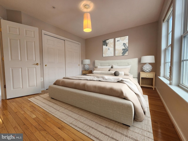 bedroom with a closet, wood-type flooring, and baseboards