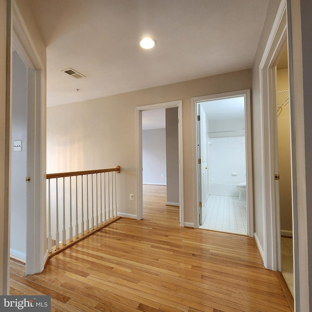 corridor featuring light wood finished floors, visible vents, and baseboards