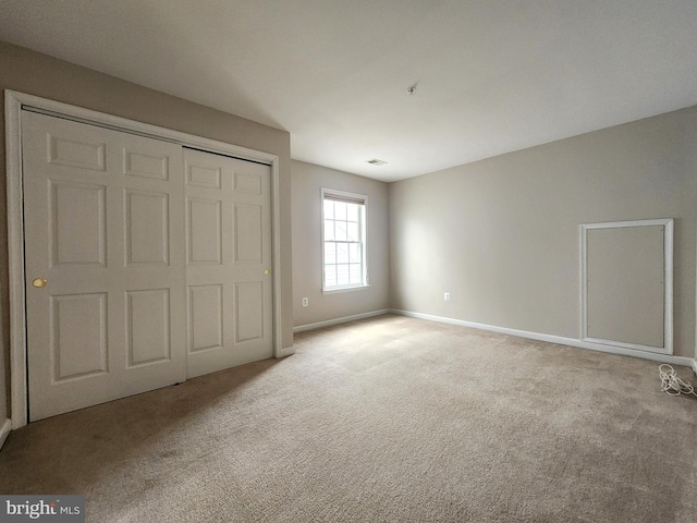 unfurnished bedroom with a closet, carpet, visible vents, and baseboards