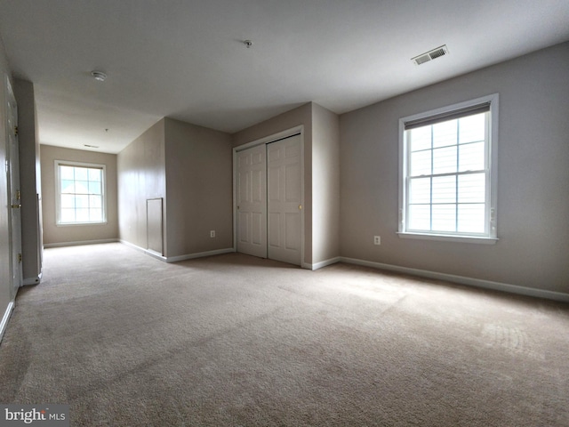 unfurnished bedroom with carpet floors, baseboards, visible vents, and a closet