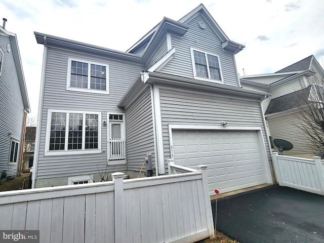 view of side of home with a garage, aphalt driveway, and fence