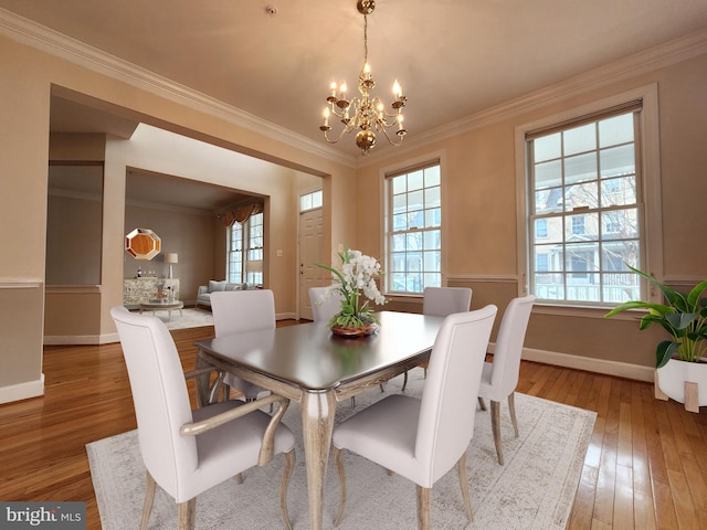 dining room with ornamental molding, baseboards, a notable chandelier, and hardwood / wood-style floors