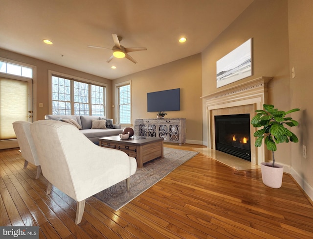 living room with hardwood / wood-style floors, a tiled fireplace, recessed lighting, and baseboards