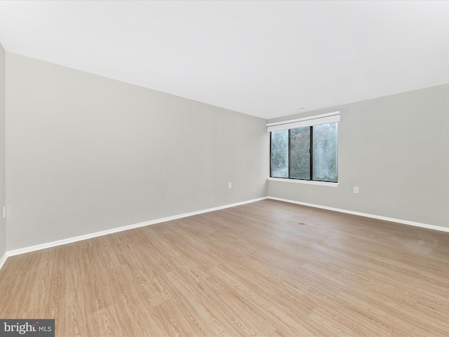 unfurnished room with baseboards and light wood finished floors