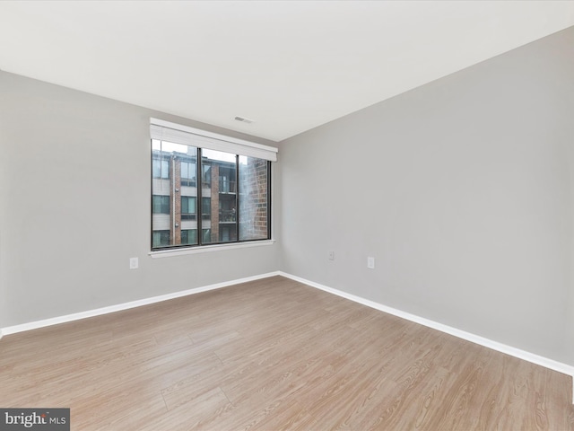 unfurnished room featuring wood finished floors, visible vents, and baseboards