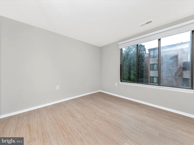 unfurnished room featuring visible vents, baseboards, and wood finished floors