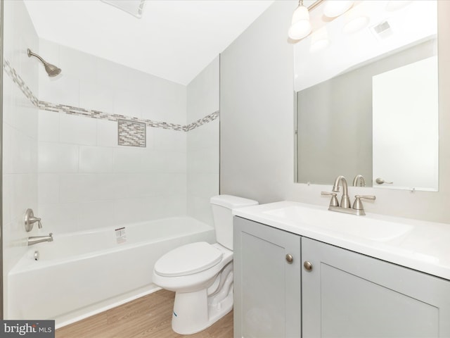 bathroom featuring toilet, wood finished floors, visible vents, vanity, and tub / shower combination