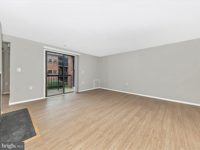 unfurnished living room with baseboards, visible vents, and wood finished floors