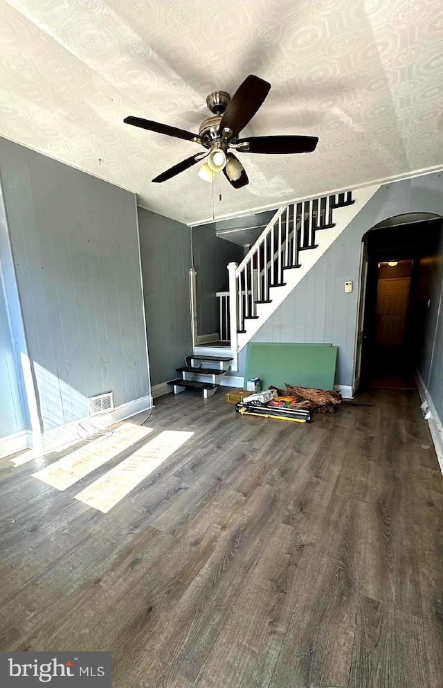 unfurnished living room featuring visible vents, arched walkways, ceiling fan, wood finished floors, and a textured ceiling