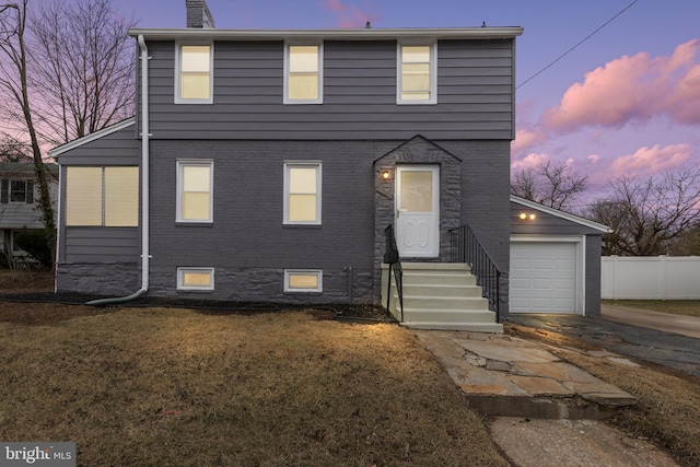 view of front of property with driveway, a chimney, fence, a yard, and brick siding