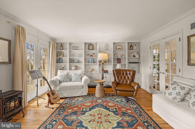 living room with ornamental molding, french doors, wood finished floors, and a wood stove