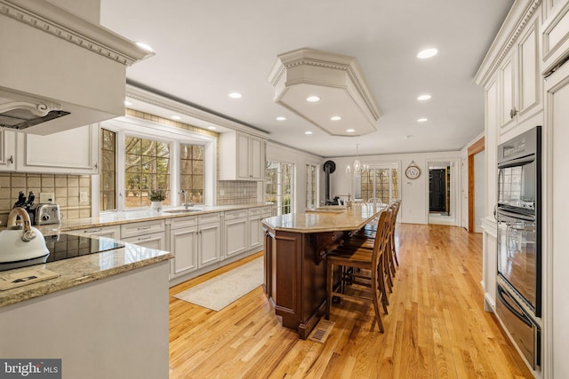 kitchen featuring a breakfast bar, a center island, black appliances, a sink, and a warming drawer