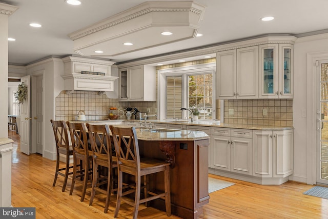 kitchen featuring a kitchen island with sink, light wood-style flooring, and a kitchen bar